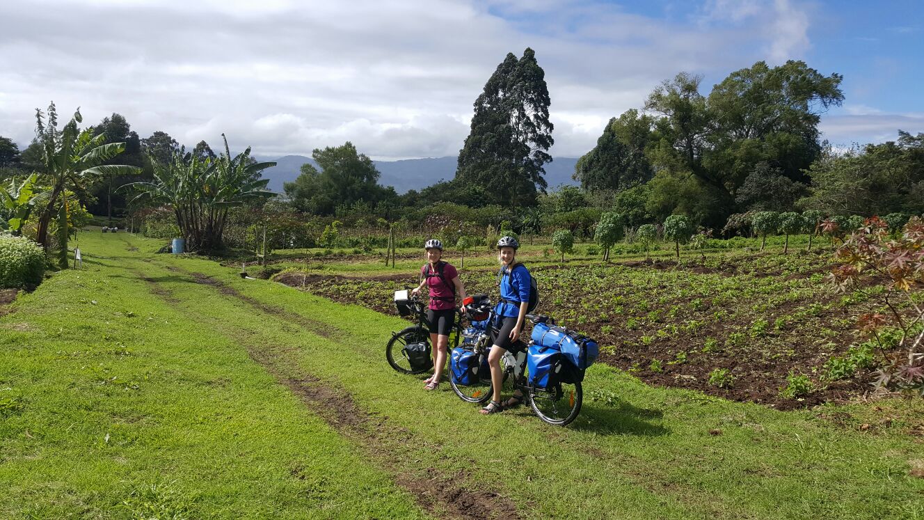 Jana und Jenni mit ihren beladenen Reiserädern in einer grünen Landschaft in Costa Rica